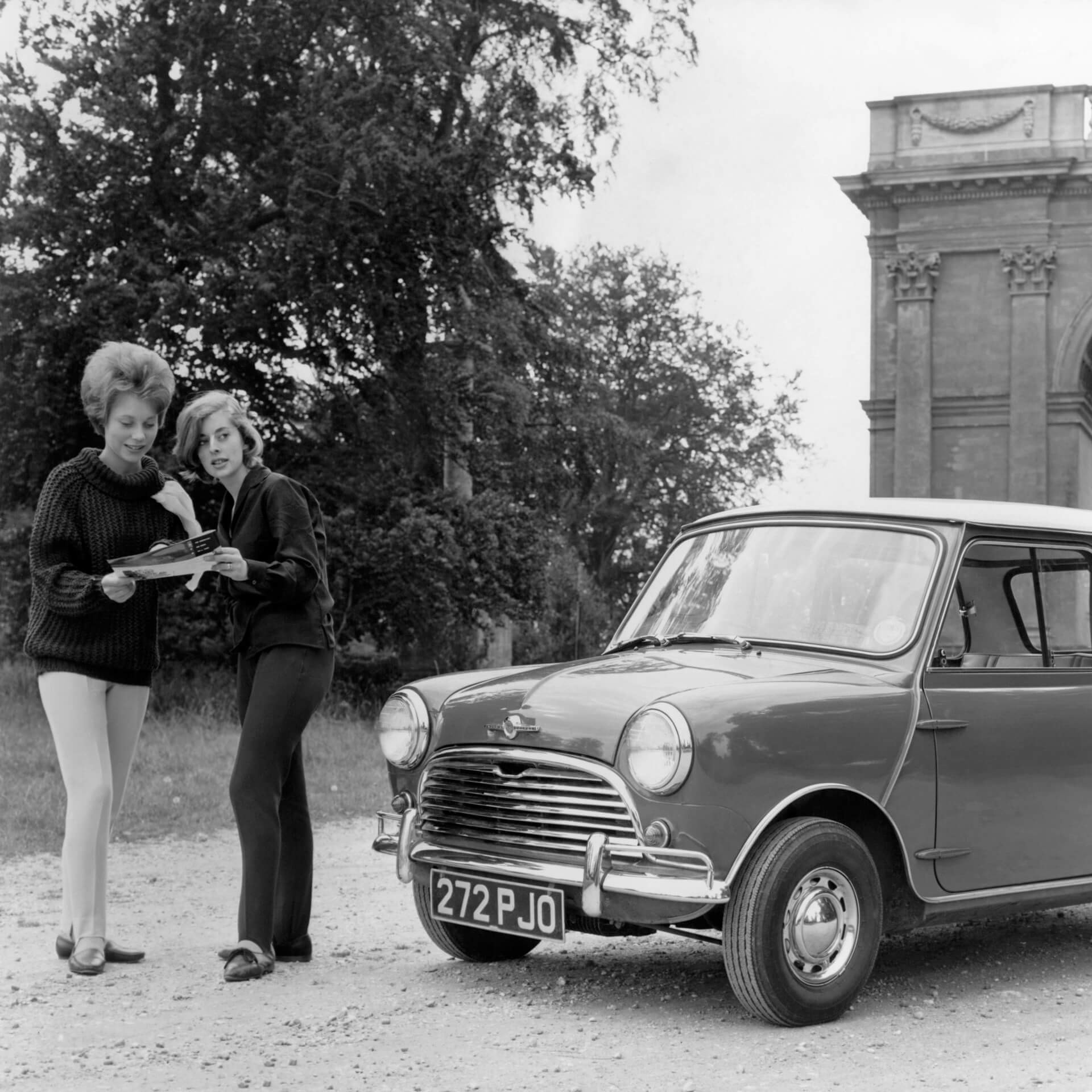 Two women studying a map standing next to a Morris Mini-Minor.